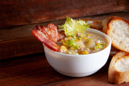 Corn chowder soup with bacon. Brown wooden background. Close-up viewの写真素材