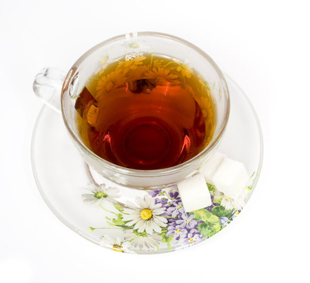 Tea cup on a saucer with sugar and green ornamentの写真素材