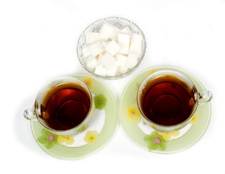 Two tea cups on a saucer with sugarの写真素材