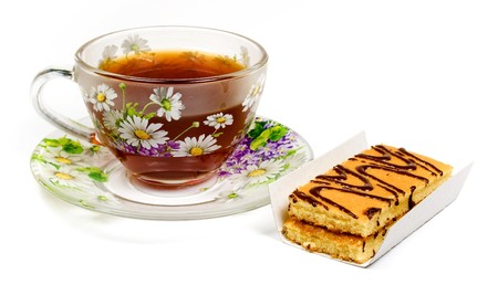 Cap of tea on saucer with cake on whiteの写真素材