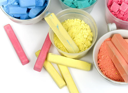 Several colors crushed chalk in tubes and caps on white