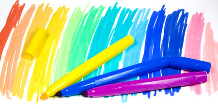 Three color felt-tip pens with one removed cap on a multi-colour backgroundの写真素材