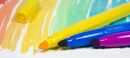 Three color felt-tip pens with one removed cap on a multi-colour background close-upの写真素材
