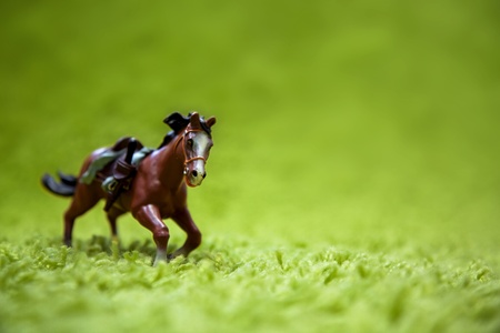 miniature toy horse in running posture on a carpet like grassの写真素材