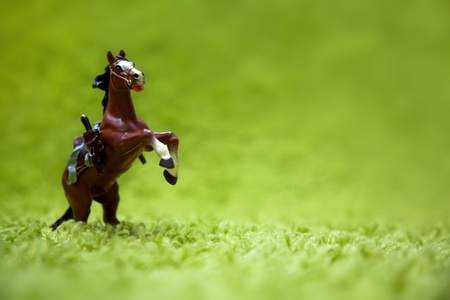 miniature toy horse in running posture on a carpet like grassの写真素材
