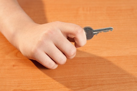 hand holding a key on a brown backgroundの写真素材