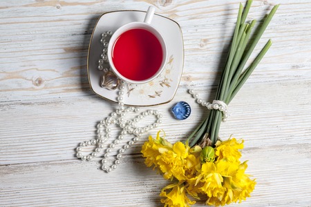 tea and daffodils on white table with vintageの写真素材