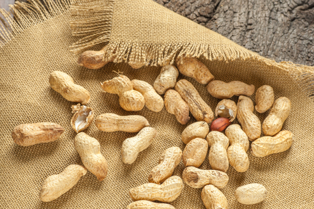 peanuts on sackcloth and old wooden plateの写真素材