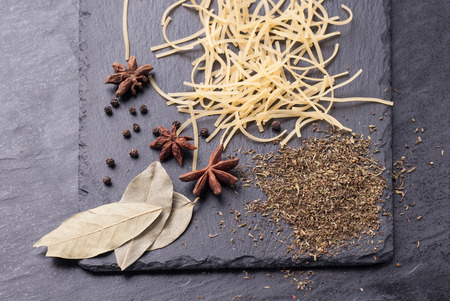 Raw pasta and ingredients on a black graphite boardの写真素材