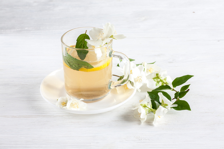 Cup of tea with jasmine flowers on a wooden tableの写真素材