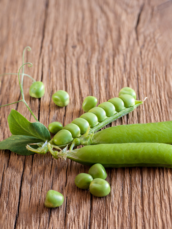 Fresh green pea on old wooden background. Vegetarian food.の写真素材