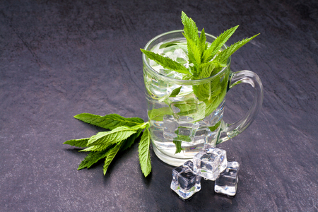 Soft drink with mint and ice in cup of glass on black stone backgroundの写真素材