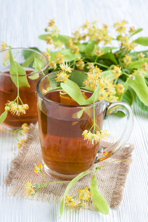 Tea with lime flower on white wooden table. Natural remedy.の写真素材