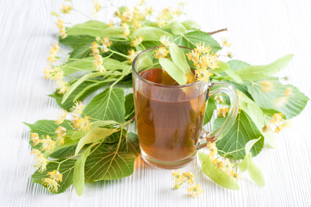 Tea with lime flower on white wooden table. Natural remedy.の写真素材