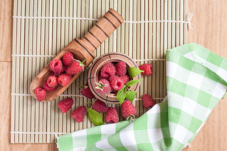 Rasberry in wooden bowl on wooden background. Natural food.