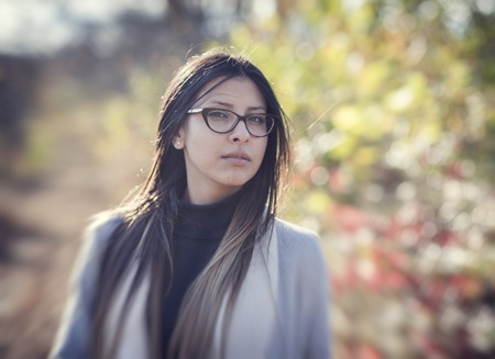 Portrait of a beautiful girl in glasses in autumn parkの写真素材