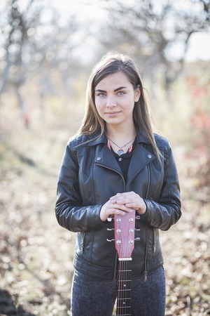Portrait of a girl with a guitar in the autumn parkの写真素材
