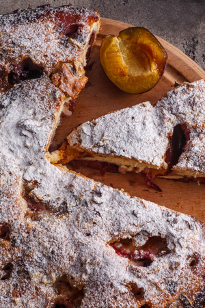 Pie with plums and fresh plums on wooden table. Homemade trditional foodの写真素材