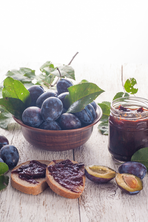 Fresh plums with homemade jam on wooden tableの写真素材