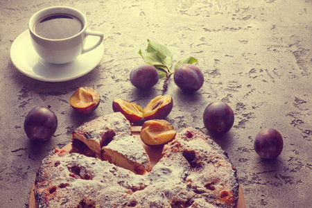 Pie with plums and cup of coffee on wooden table. Homemade traditinol food.の写真素材