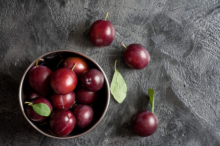 Fresh plums in metal bowl on a stone backgroundの写真素材