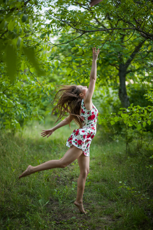 pretty young woman jumping on green park after his hatの写真素材