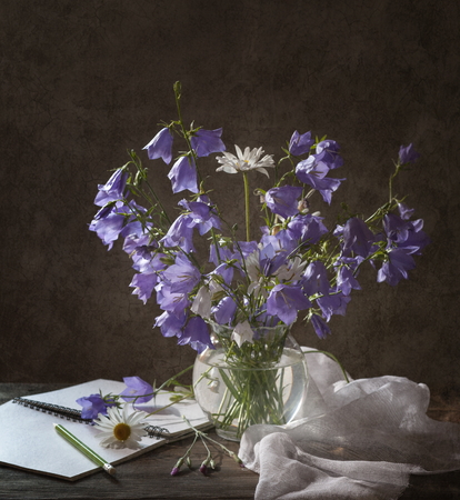 Beautiful bell flower bouquet in the vase on wooden table. Still life with bell shaped flowers.の写真素材