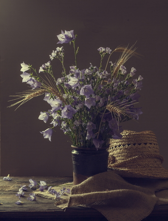Beautiful bell flower bouquet in the vase on wooden table. Still life with bell shaped flowers.の写真素材