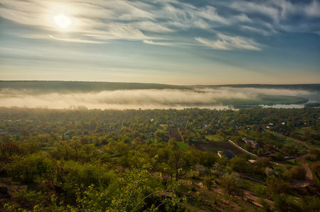 River scenery in the early morning. A hut in far away, and the tree covered by mystical fog, very...