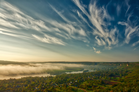 River scenery in the early morning. A hut in far away, and the tree covered by mystical fog, very quiet and tranquil. Beautiful sunrise give red ambient in to the fishpond environmentの写真素材