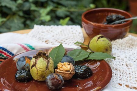 Fresh and dried prunes whit walnuts on plate. Natural food. Outdur composition. Close up.の写真素材