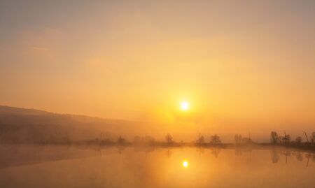 Sunrise over foggy lake.の写真素材