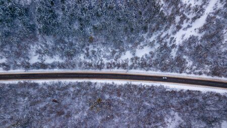 Country road going through the beautiful snow covered landscapes. Aerial view. Drone photographyの写真素材