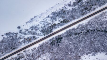 Country road going through the beautiful snow covered landscapes. Aerial view. Drone photographyの写真素材