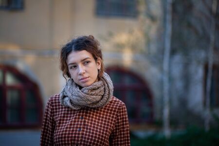 Dreaming young woman with spectacular curly red ginger hair looking at camera posing outdoor in downtown street. Female portrait.の写真素材