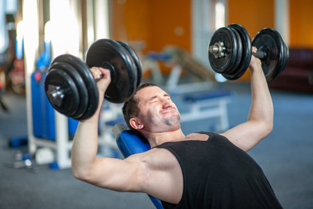 Strong man lifting weight in sport club. Closeup guy training muscles with dumbbells in gym....