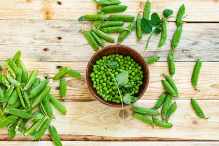 closeup green peas in brown dish, on wooden table.の写真素材