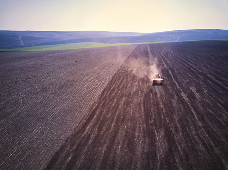 Tractor in a field performing spring sowing., top view from drone pov