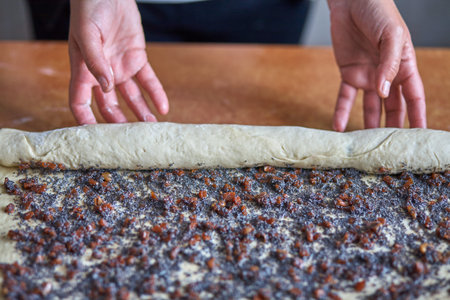 Woman rolls dough with jam for baking.