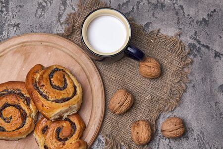 Basket of homemade buns with jam, served on old wooden table with walnuts and cup of milkの写真素材