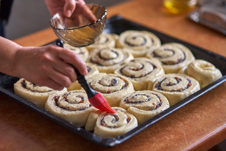 A silicone pastry brush covers fresh buns. Making home biscuit rollsの写真素材