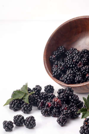 Blackberries in a wooden bow. Ripe and tasty black berry isolated on white. Blackberries on a white background.の写真素材