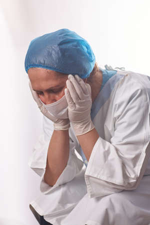 Portrait of a female doctor/surgeon feeling down, exhausted, frustrated, very tired, .... on white backgroundの写真素材