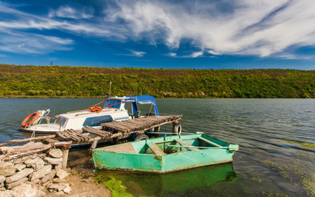Small oar fishing boat moored on a river with reflection