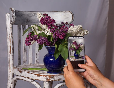 photographer, blogging workshop concept. hand holding phone and taking photo of stylish flower