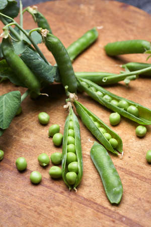 Fresh green peas pods on a wooden board.の写真素材
