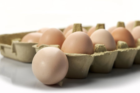 Close-up of eggs in cartoon on white background. Raw chicken eggs in egg box organic food for good...