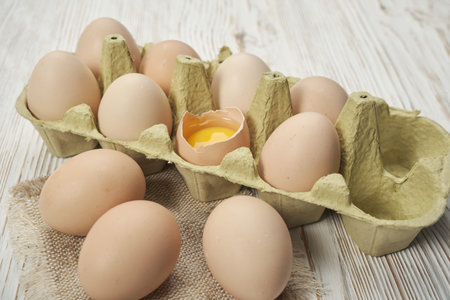 Close-up view of raw chicken eggs in egg box on wooden background. Raw chicken eggs in egg box...
