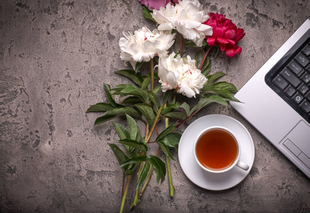 Coffe, peonies and laptop on gray vintage backgroundの写真素材