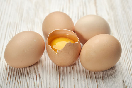 Close-up view of raw chicken eggs in egg box on wooden background. Raw chicken eggs in egg box...